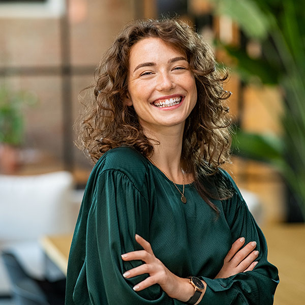 About Us Woman in Green Shirt Smiling Indoors